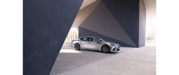 Ein silberner Lexus LS steht geparkt unter einer geometrischen Betonkonstruktion