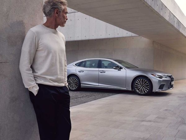 A person stood in the foreground of a Lexus LS