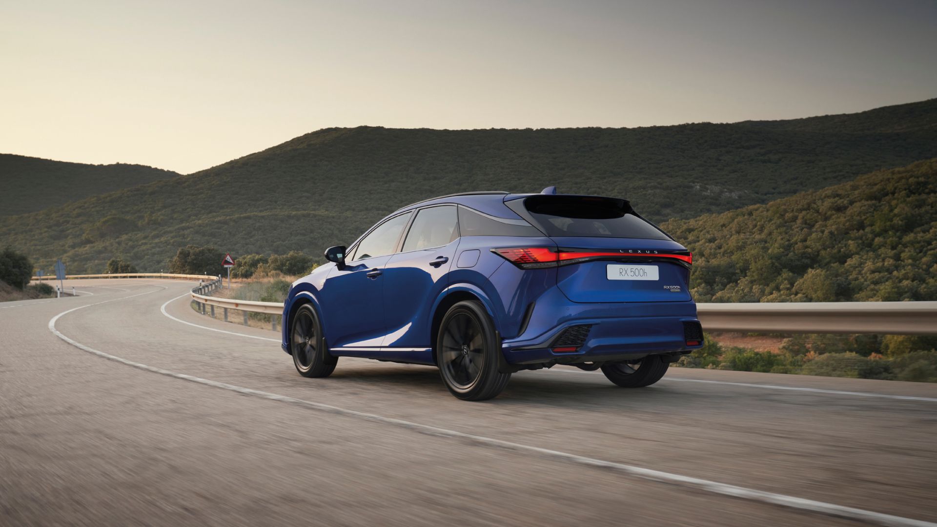 A blue Lexus RX hybrid model driving round a corner