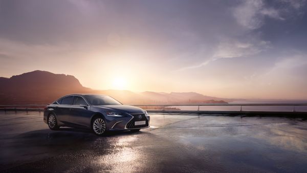 Ein dunkelgrauer Lexus ES geparkt an einer Küste vor einem Sonnenuntergang