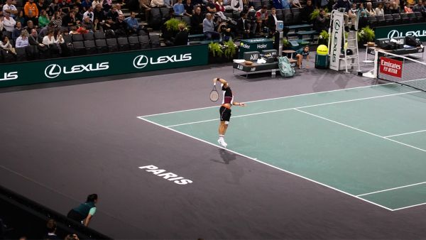 A tennis player serving on a Lexus X ATP court