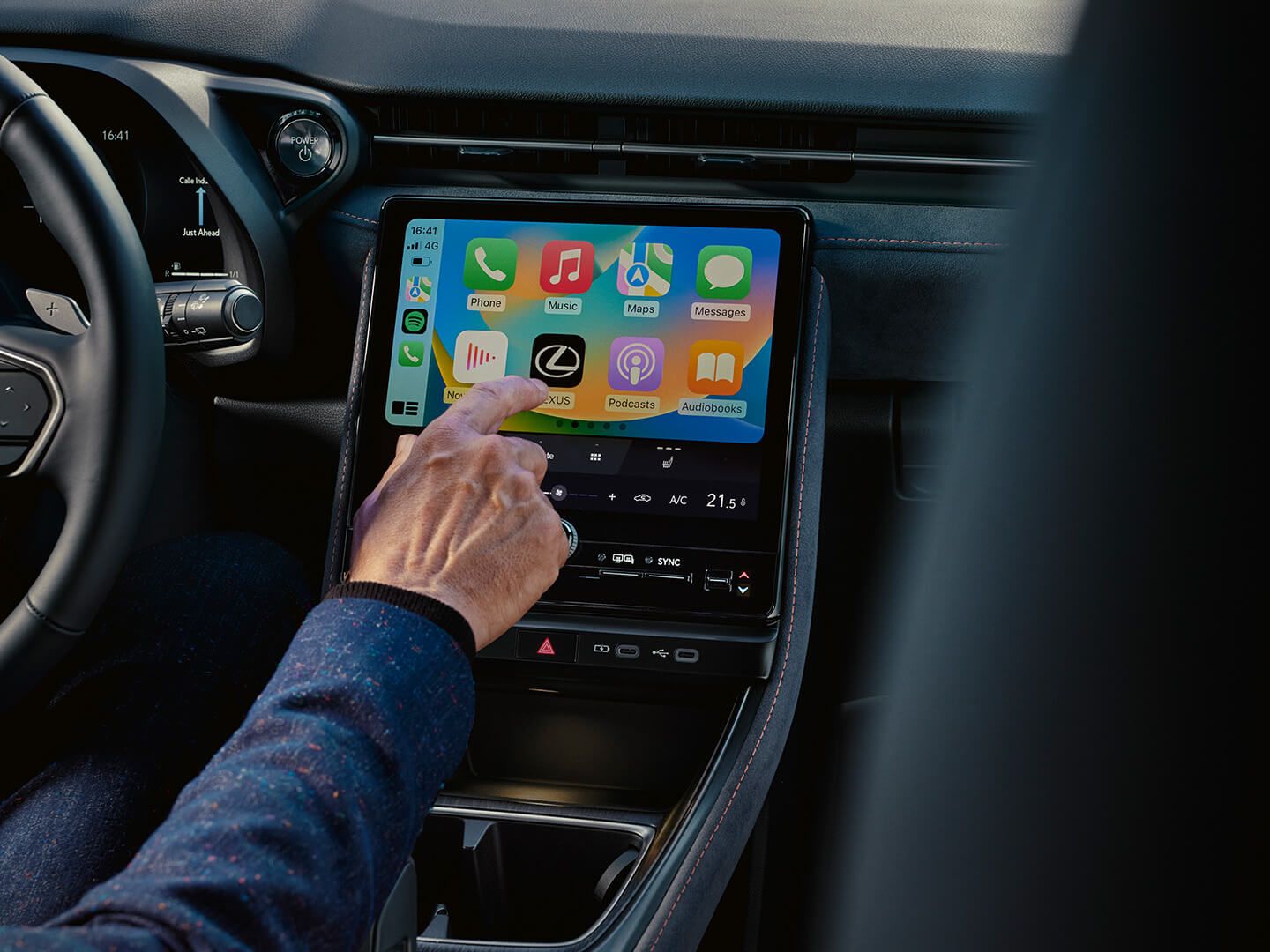 A person driving a car with an Apple Car display in the Lexus LBX interior.