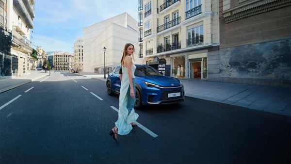 A person walking towards a parked Lexus LBX