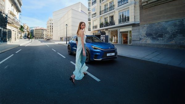 A person walking towards a parked Lexus LBX