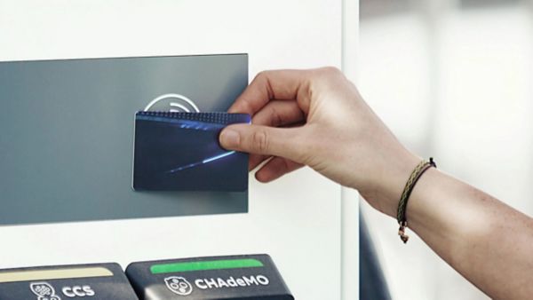 Eine Hand hält eine Ladekarte gegen einen NC-Chip-Leser einer Ladesäule.