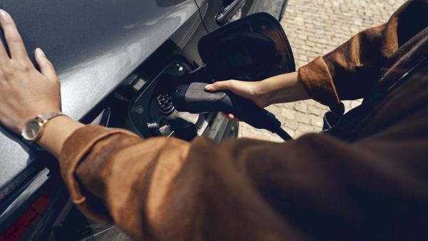 Eine Person ist dabei ein Kabel in die Ladebuchse zu stecken, um sein Auto zu laden.