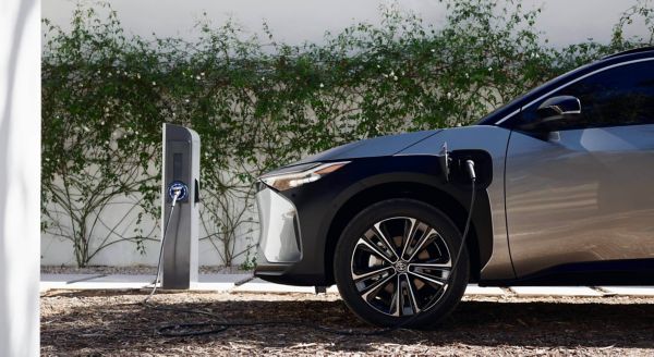 Ein modernes Elektroauto lädt an einer öffentlichen Ladesäule auf einem Parkplatz mit begrüntem Hintergrund. Die Aufnahme zeigt den Ladevorgang eines E-Autos mit Typ-2-Ladekabel – ein Beispiel für das komfortable und klimafreundliche Elektroauto laden im Alltag.