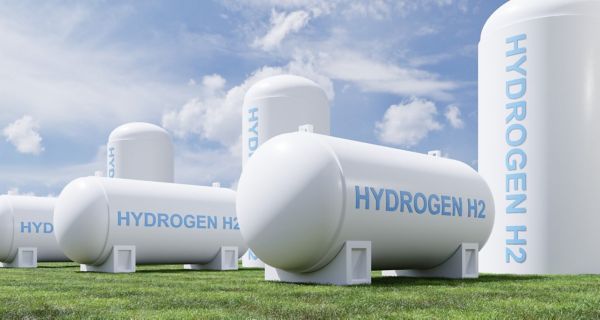 Mehrere weiße Tanks mit der Aufschrift "Hydrogen H2" stehen auf einem Rasen unter blauem Himmel