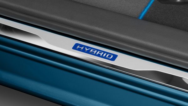 Nahaufnahme eines blauen Hybrid-Symbols auf einer silbernen Fußleiste eines blauen Hybridautos.