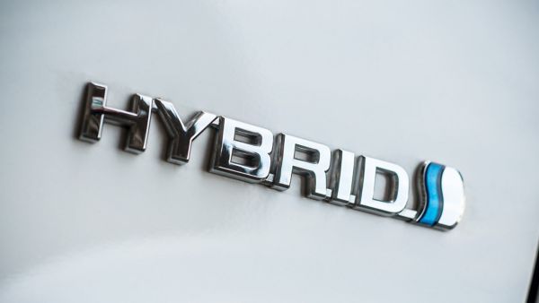 Nahaufnahme eines silbernen Hybrid-Logos auf weißer Karrosserie.