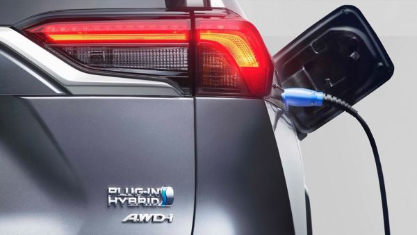 Nahaufnahme eines Plug-In Hybrid Hecks mit Fokus auf die Rückleuchte. An der Seite hängt ein Kabel aus der Ladebuchse.
