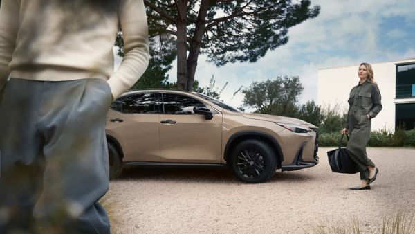 Two people walking near a parked Lexus