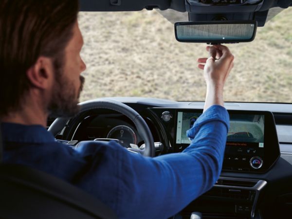 A person looking into the rear view mirror of a Lexus