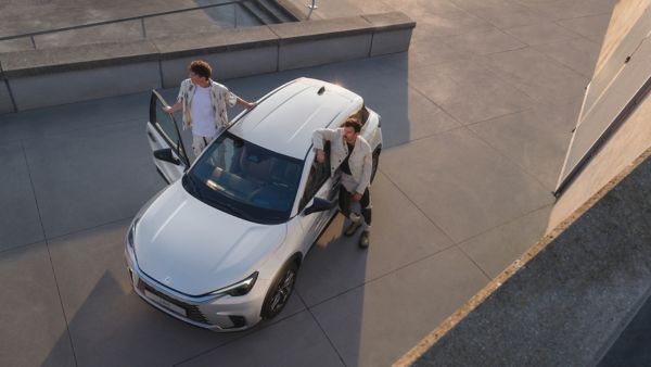 A driver and passenger stood next to a parked Lexus