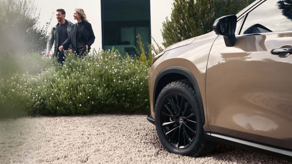 Lexus NX wheel close-up with two people in the background