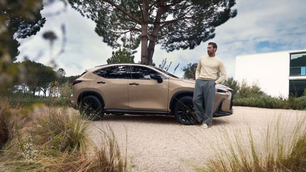 A person leaning against a parked Lexus NX