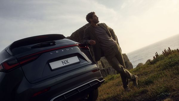 A person leaning against a parked Lexus NX