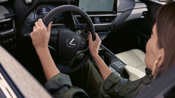 Eine Person sitzt am Steuer eines Lexus und hält mit beiden Händen das Lenkrad