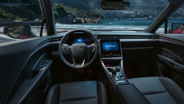Innenansicht eines Lexus mit eleganten Designelementen, einem modernen Armaturenbrett und einem malerischen Küstenhintergrund, der durch die Windschutzscheibe sichtbar ist.