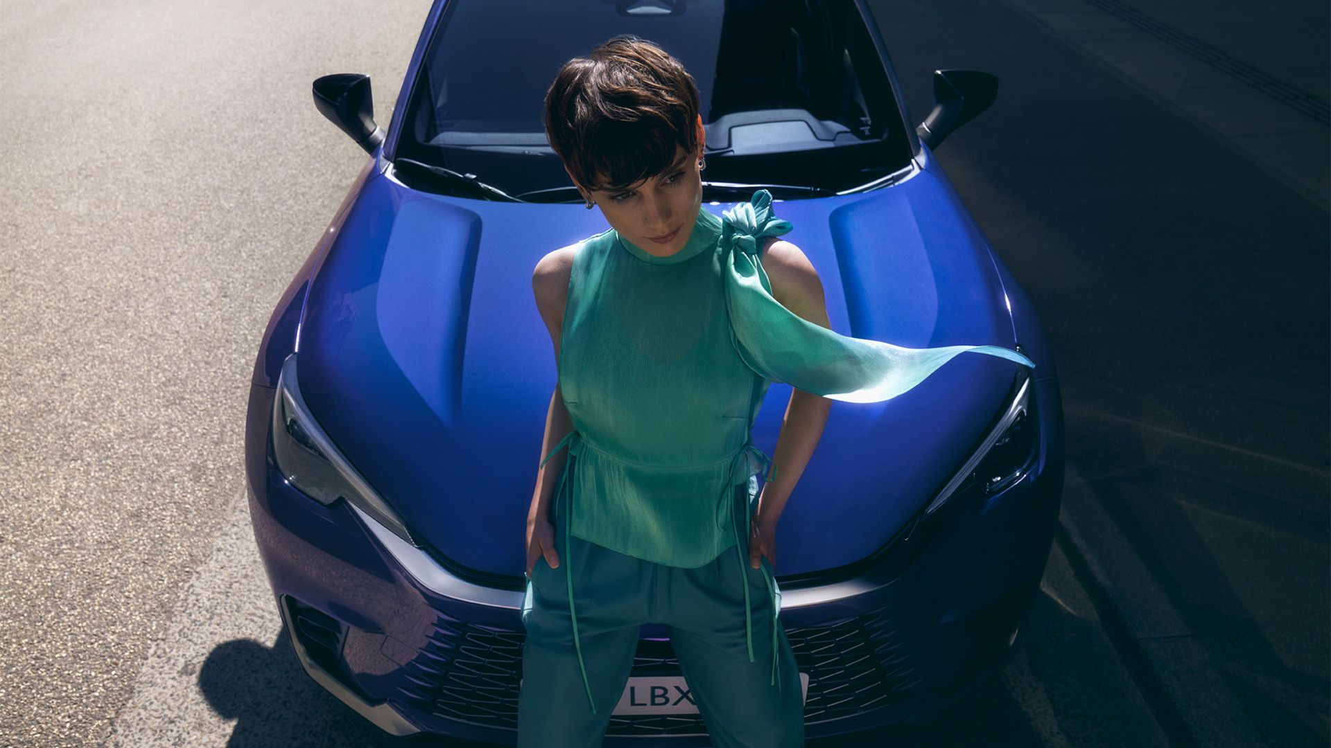 mulher à frente de um Lexus azul