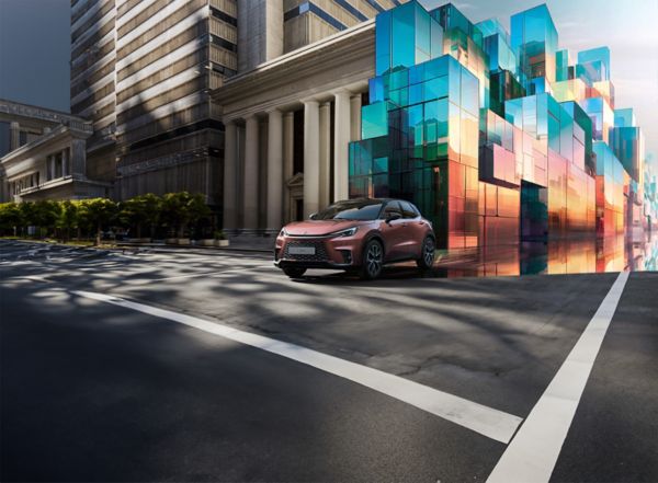 Ein eleganter, moderner Lexus LBX SUV fährt auf einer städtischen Straße und spiegelt die umgebende Architektur in seinem glänzenden Finish wider.