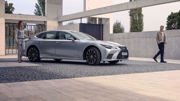 Two people walking away from a parked Lexus LS