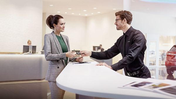 A Lexus employee handing a customer a courtesy car key