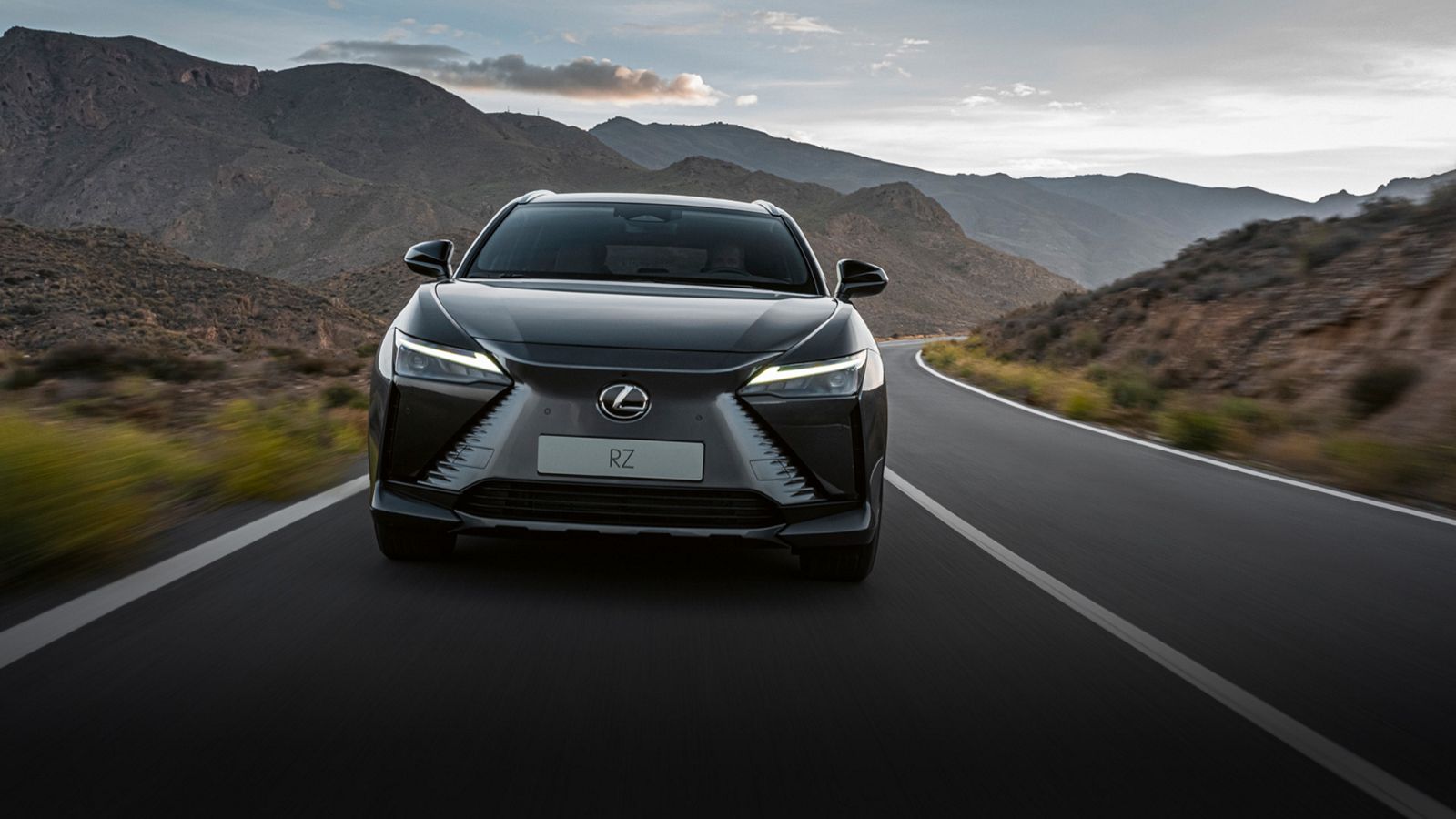 The front of a Lexus RZ driving on a rural road