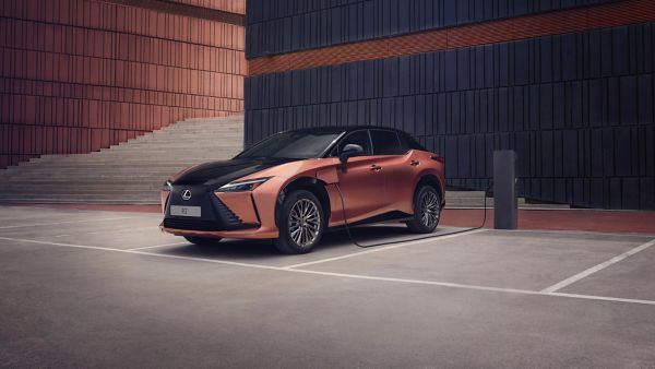 Ein elektrisch betriebener Lexus RZ, geparkt in einer modernen städtischen Umgebung, mit einem eleganten schwarz-kupfernen Design und einer Ladestation in der Nähe.