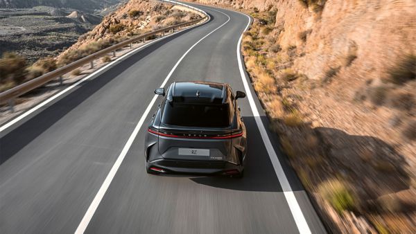 Rear view of a Lexus RZ 450e driving in a mountainous location