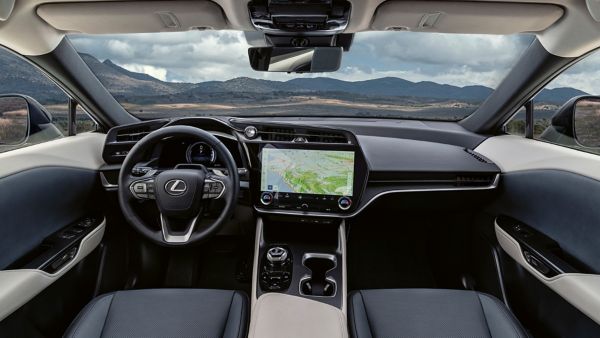 Innenansicht eines Lexus RZ mit Lenkrad, Armaturenbrett und großem Bildschirm, auf dem eine Landkarte mit Bergen im Hintergrund zu sehen ist.