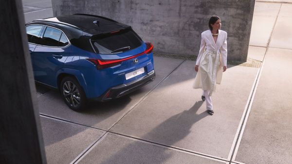 A woman walking past a parked Lexus LBX
