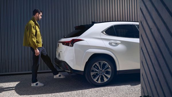 Een persoon staat achter een witte Lexus UX