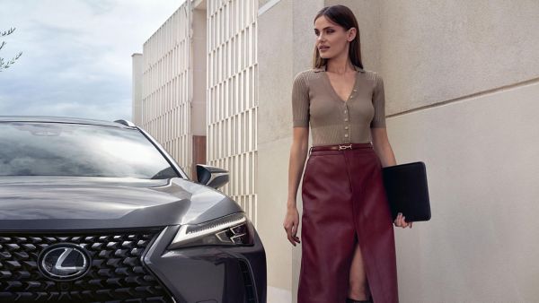 Eine Person steht neben einem Lexus, der an einer Hauswand geparkt ist