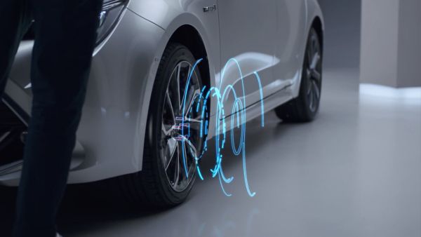 Nahaufnahme von Felgen eines silbernen Autos mit grafischer Visualisierung, wie neue Energie beim Fahren erzeugt wird.