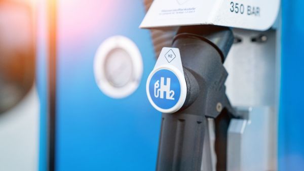 Nahaufnahme einer Zapfpistole an einer blauen Zapfsäule mit der weißen Aufschrift "H2"