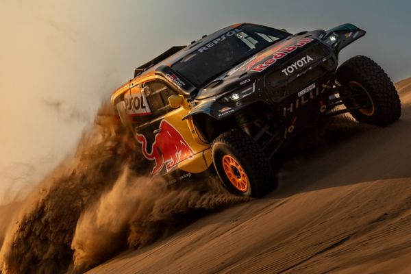 A Toyota GR DKR Hilux Evo races across a steep dune