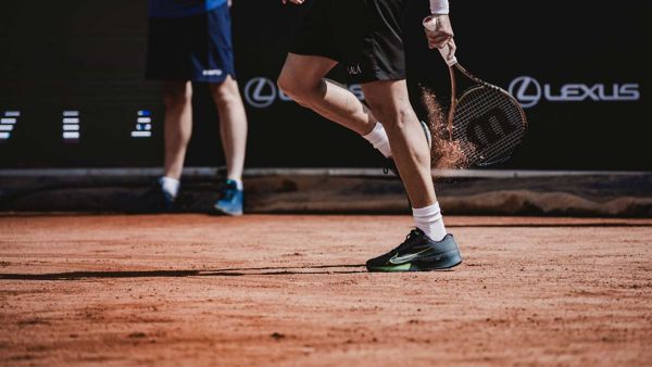 A closeup of a Tennis player's legs on a clay court.