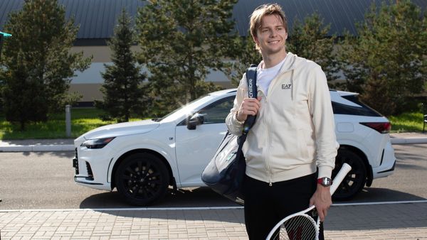 Alexander Bublik holding a tennis racket with a Lexus in the background