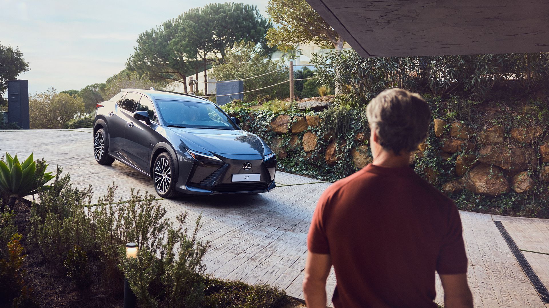 Una persona si avvicina a una Lexus RZ parcheggiata in un vialetto