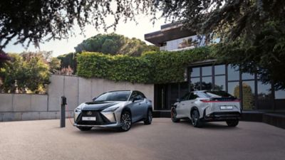 Zwei Lexus RZ, die vor einem Haus geparkt sind.