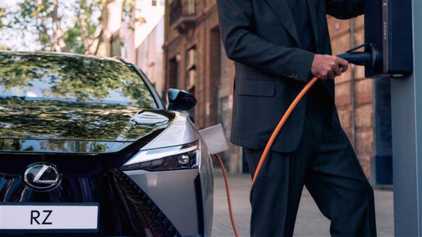 A person plugging a parked Lexus RZ into a HomeCharge charging system