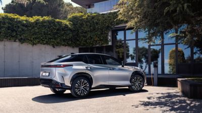 Ein Lexus RZ, der vor einem Haus geparkt ist.