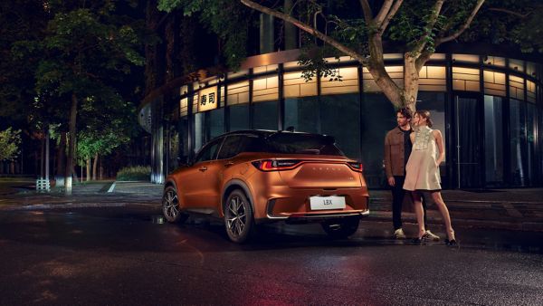 Two people stood next to a parked Lexus LBX