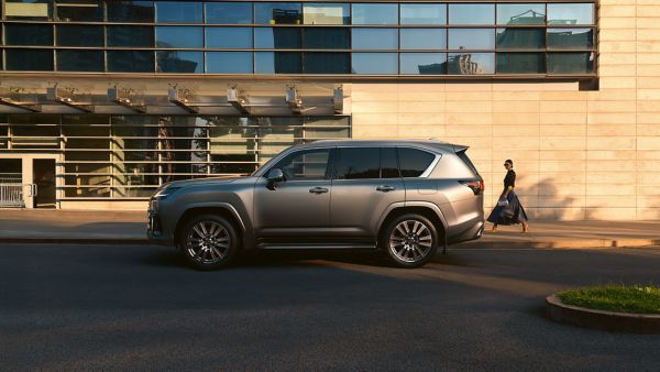 A person walking past a parked Lexus LX