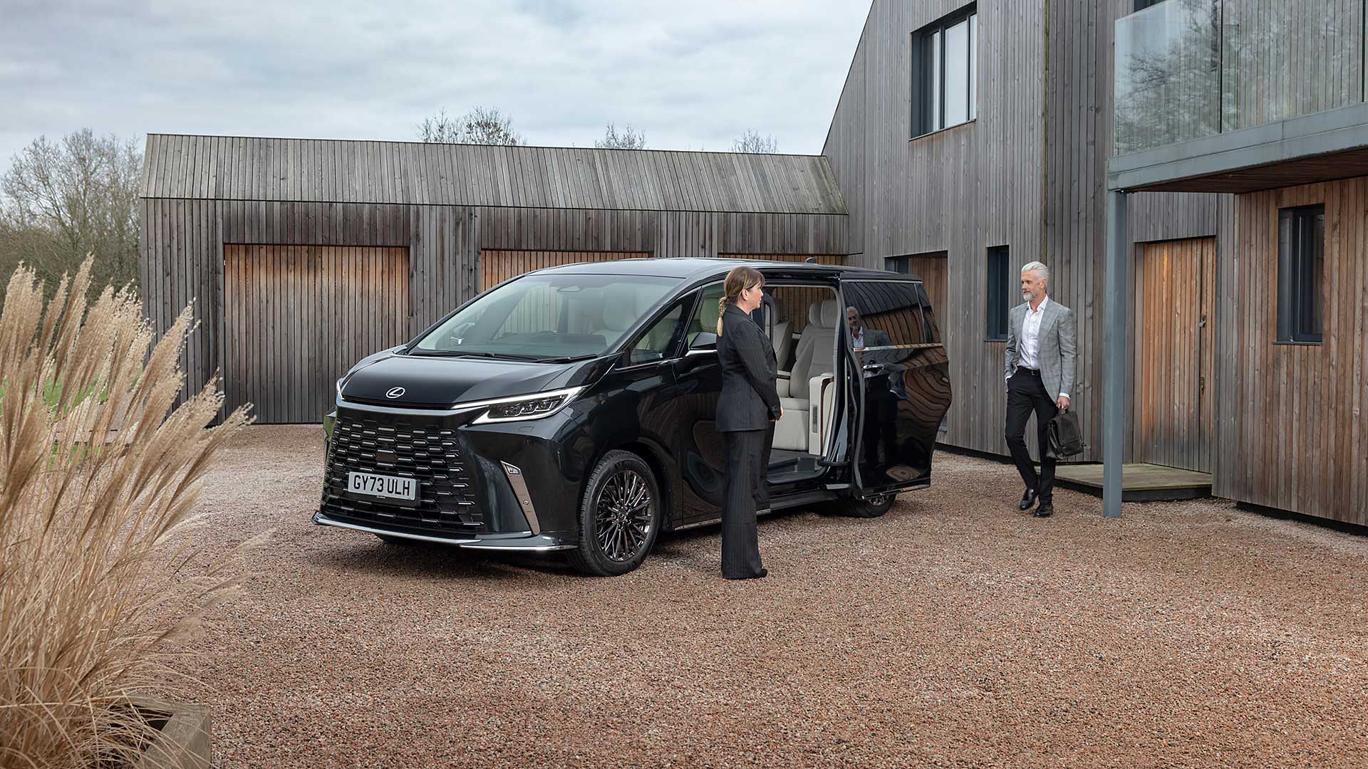 A driver and passenger stood next to a Lexus LM