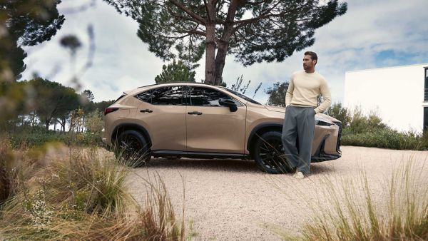 Een persoon leunend tegen een geparkeerde Lexus NX