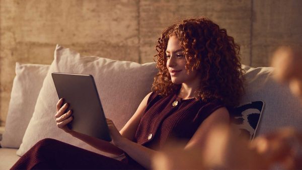 A woman using a tablet device sat on a sofa