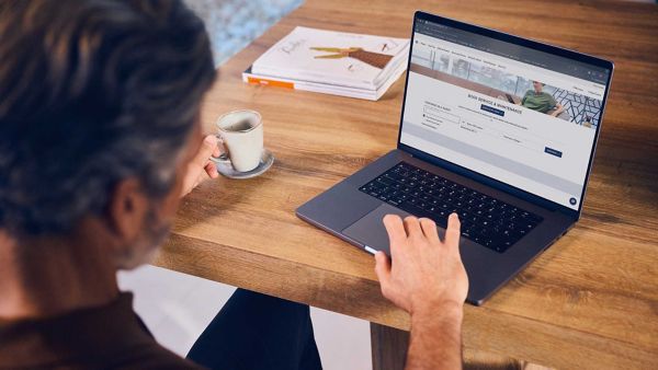 Ein Lexus-Besitzer, der über einen Laptop auf die Online-Servicebuchung zugreift
