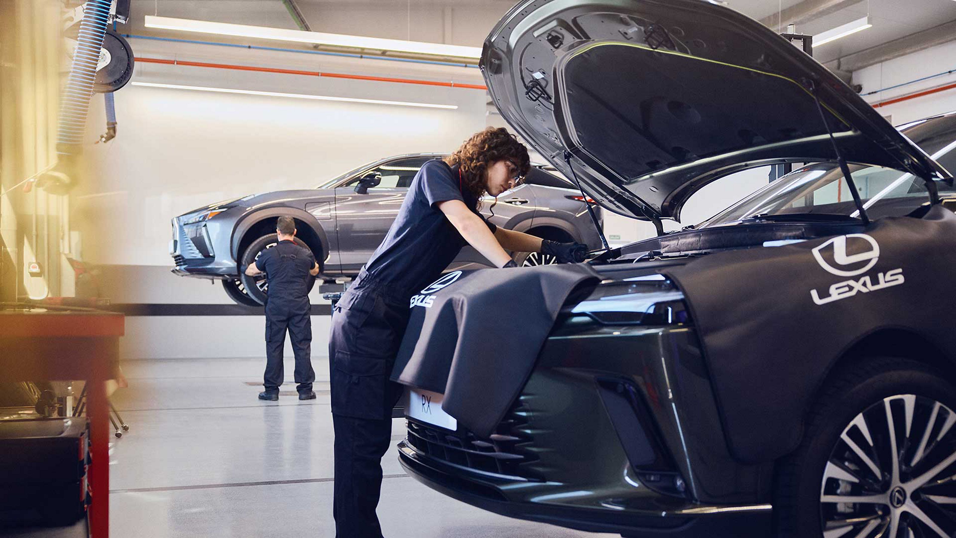 Un técnico de Lexus trabajando bajo el capó de un Lexus RX